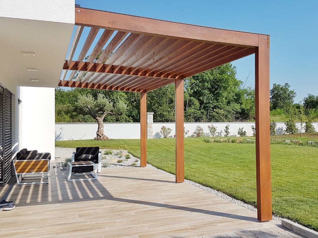 Wooden slatted pergola spanning modern patio with lawn view