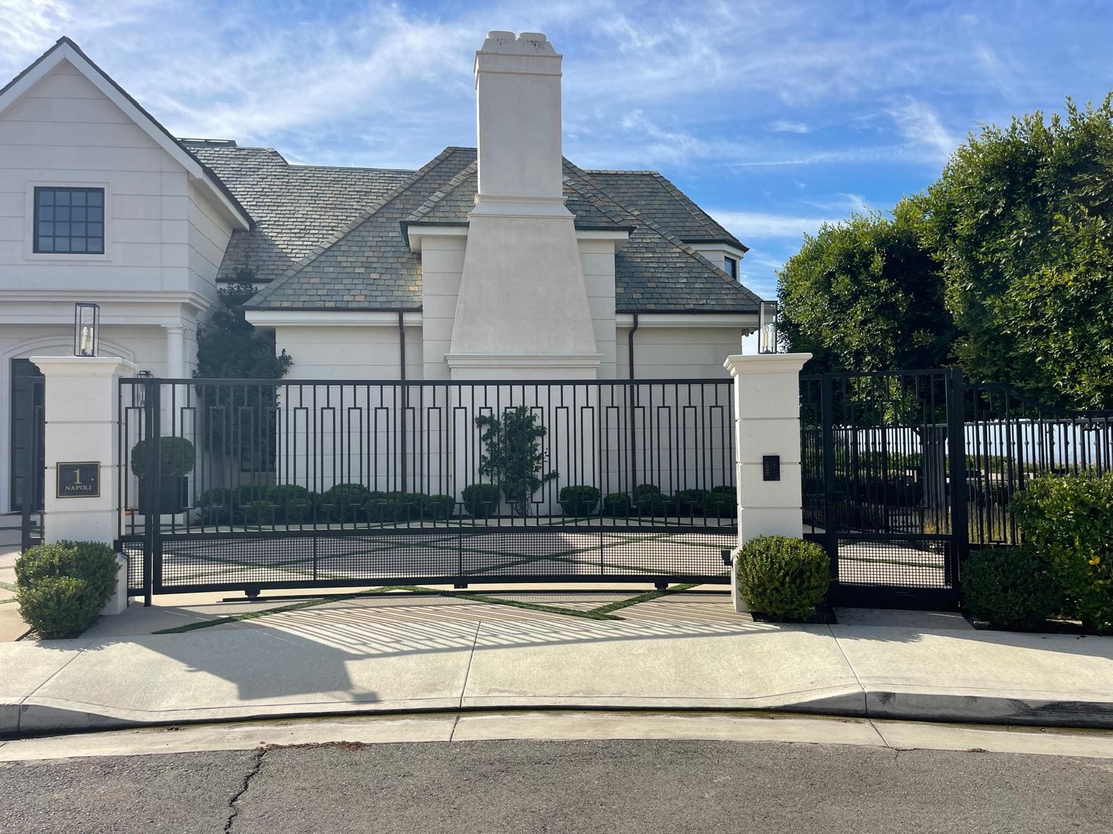 Wrought iron fence and driveway gate with white pillars at a Southern California home
